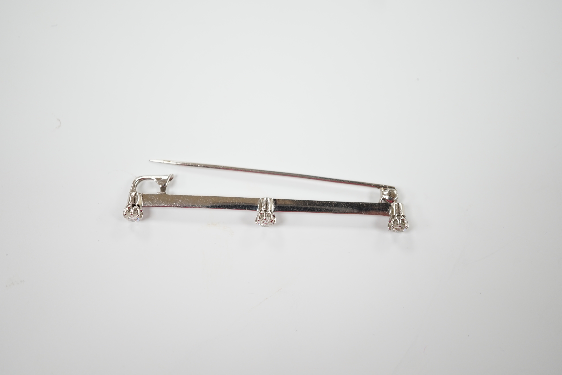 A white metal and three stone diamond set bar brooch, 56mm, gross weight 3.4 grams.